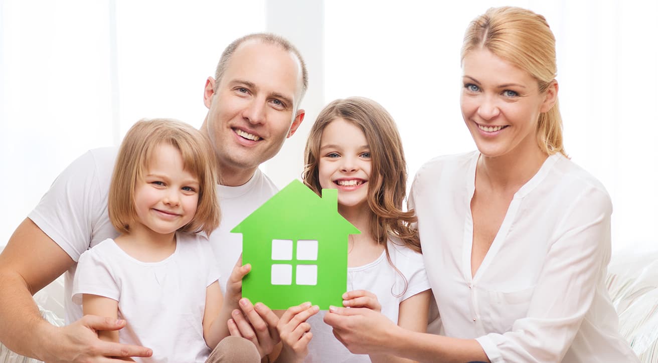 Mosolygó család ház alakú jelképet tart, a kulcsrakész családi ház kivitelezés otthonteremtő eredményét szimbolizálva.