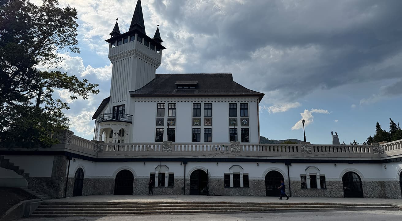 Felújított történelmi épület toronnyal és díszített homlokzattal, a műemléki értékmegőrzés és korszerűsítés példájaként.