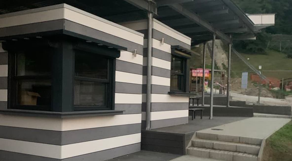 Csíkos homlokzatú árusító pavilon fedett terasszal és lépcsős megközelítéssel.