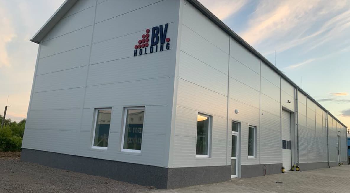 BV Holding raktárcsarnok külső nézete világos homlokzattal és ipari kapuval.