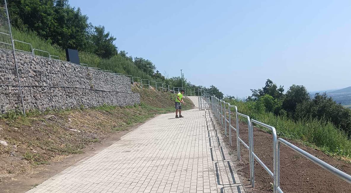 Burkolt gyalogos út és támfal a kötélhídhoz vezető rendezett közlekedési útvonal mellett.