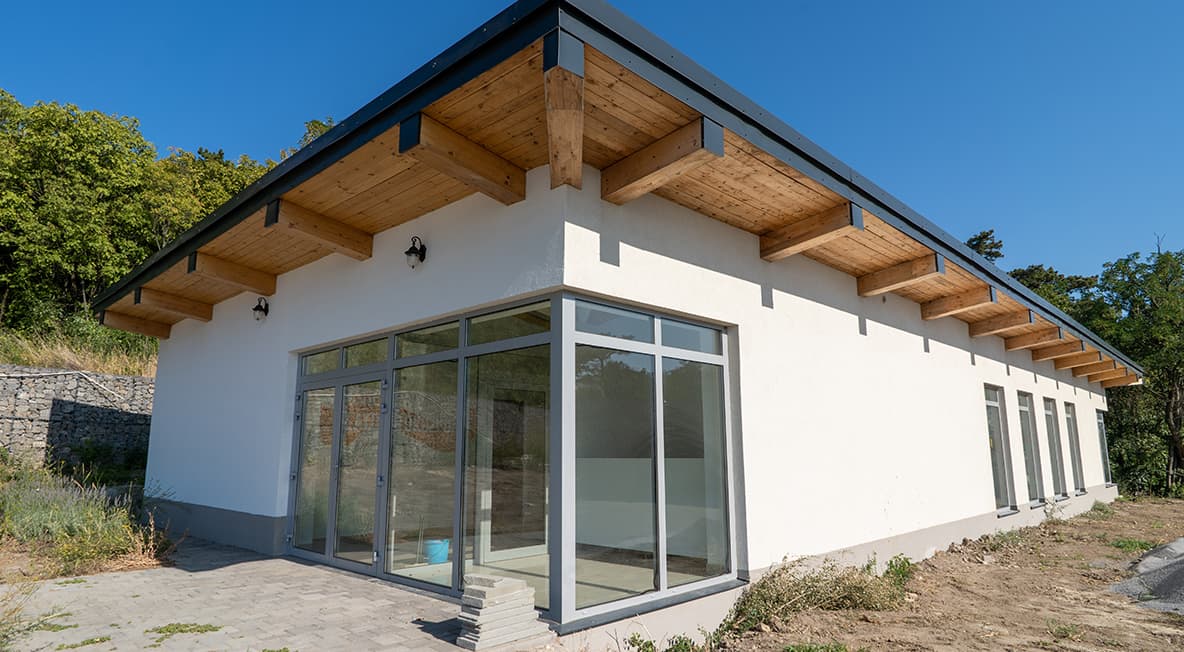 Várfogadó épület nagy üvegfelületekkel és modern, alacsony hajlású tetős kialakítással.